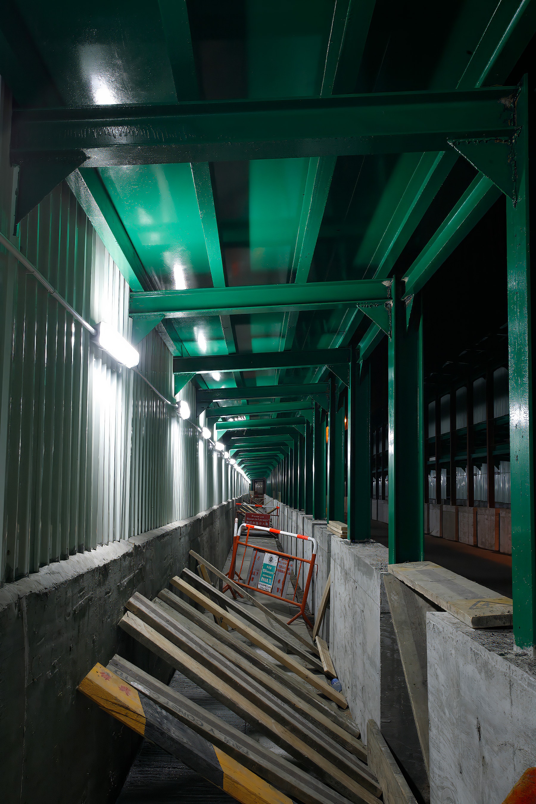 Industrial corridor with green steel beams and white corrugated walls