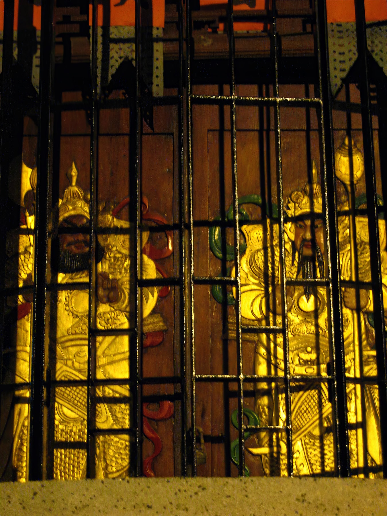 Golden religious figures behind iron bars